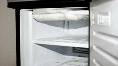 Leerer, geöffneter Kühlschrank mit leicht vereistem Gefrierfach