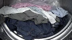 Bunte Wäsche liegt in einer Trommel einer Waschmaschine zur Reinigung bereit.