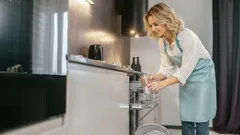 Frau räumt Geschirrspüler in moderner Küche ein, Hausarbeit im Alltag